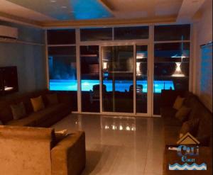 Al KarāmahCali Chalet的带沙发和大窗户的客厅