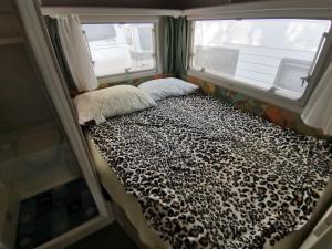 乌格连Room in Cabin - Caravan near the sea 5的一张小床,位于带两个窗户的房间