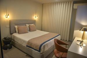 波尔图美洲酒店的一间卧室配有一张床和一张桌子及椅子