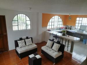 安巴托4 Suite Balcón estelar Ambato的客厅配有两把椅子和一张桌子,厨房配有