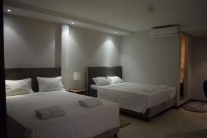 帕拉马里博Hotel RITZZ的一间卧室配有两张带白色床单的床