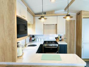 斯卡伯勒The Hideaway的厨房配有白色橱柜和炉灶烤箱。