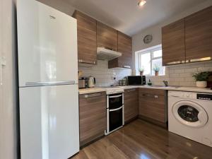 WellingCentral Welling Flat的厨房配有冰箱、洗衣机和烘干机