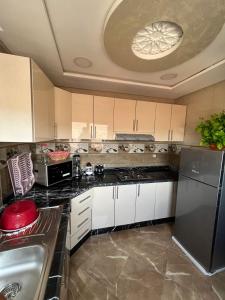 海尼夫拉APPART HOTEL OUED EDDAHAB的厨房配有白色橱柜和不锈钢冰箱