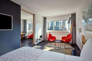 美因河畔法兰克福法兰克福艾美度假酒店的酒店客房,配有一张床和两张红色椅子