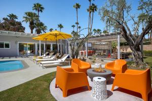 棕榈泉On The Rox- Luxury Refreshing Mid-Century Mod- Pool, Spa, Firepit, Outdoor Kitchen & More的一个带橙色椅子的户外庭院和游泳池
