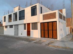 皮斯科Casa San Andrés Arenas con sala de billar的白色的建筑,街道上设有橙色门