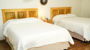 圣安娜Equinoccio Hotel的配有白色床单的客房内的两张床