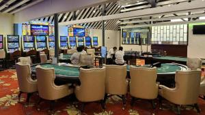 维拉港Coconut Palms Resort & Diamond Casino的扑克室配有桌椅,人们玩扑克