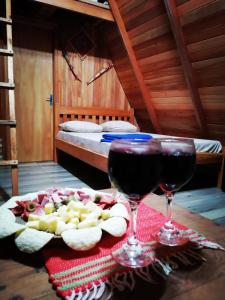 埃斯特城Cabaña del lago的一张桌子,上面放着两杯葡萄酒和一盘食物