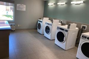 麦卡伦Baymont by Wyndham McAllen Pharr的洗衣房配有3台洗衣机和1个柜台