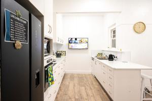 科罗瓦Fairleys of Corowa的厨房配有白色橱柜和黑色冰箱。