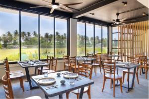 迪古拉Whaleshark Beach的餐厅设有桌椅和大窗户。