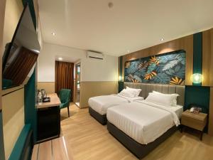 丹戎槟榔Alltrue Hotel Bintan - Tanjungpinang的酒店客房设有两张床和电视。