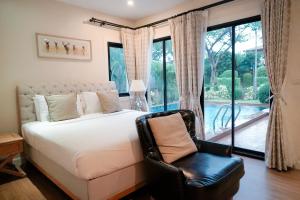 纳仲天赤湾尼芭堤雅酒店的卧室配有一张床和一张椅子,位于窗户前