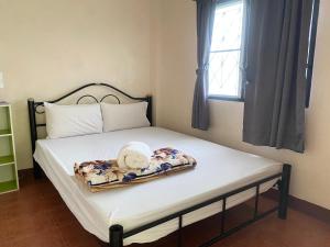 达叻府班嘉德旅馆的一张位于带窗户和床垫的房间内的床铺