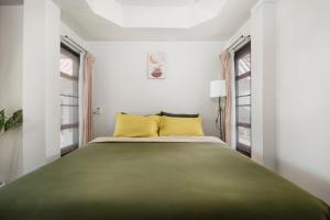 拜县Betel Palm Village - Casa Retreat的一间卧室配有一张带黄色枕头的大型绿色床。