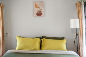 拜县Betel Palm Village - Casa Retreat的一间卧室配有一张带两个黄色枕头的床