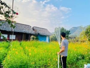 高平Luong Son Homestay Ecolodge的站在田野上,手杖的人