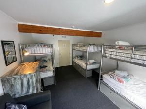 派西亚Peppertree Lodge & Backpackers的带三张双层床和一张沙发的房间