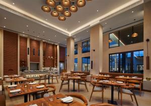 菩提伽耶Hyatt Place Bodh Gaya的餐厅设有木桌、椅子和窗户。