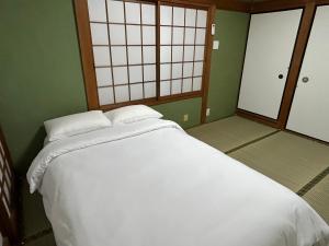 泉佐野KIX House Waraku III 和楽三号館的一张白色大床,位于带绿色墙壁的房间