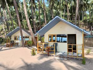 ColaCola Beach Sunset Bay的棕榈树海滩上的小屋