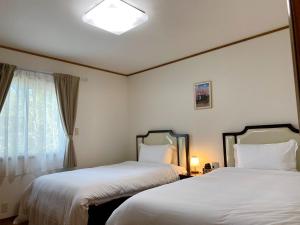 嬬恋村Chateau Ange UMAYA - Vacation STAY 68831v的配有窗户的酒店客房内的两张床