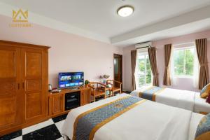 富国Luxy Park Hotel & Residences - Phu Quoc City Centre的酒店客房设有两张床和一台平面电视。