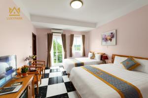 富国Luxy Park Hotel & Residences - Phu Quoc City Centre的酒店客房设有两张床和一台平面电视。