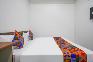 海得拉巴FabHotel Rooms 27的卧室配有白色的床和色彩缤纷的毯子
