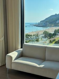 釜山Paul Mare Pool Villa的窗户前的沙发,享有海滩美景