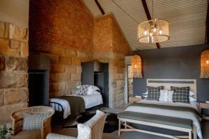克拉伦斯Andes Clarens Guesthouse的一间卧室设有两张床和石墙