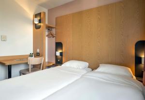 尼奥尔B&B HOTEL Niort Marais Poitevin的一间卧室配有两张白色的床和一张书桌