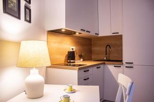 华沙Przytulne mieszkanie w Centrum的厨房配有白色橱柜和带台灯的桌子
