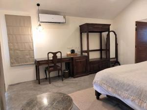 达兰萨拉Dev Bhoomi Farms & Cottages的一间卧室配有书桌、一张床和一张桌子
