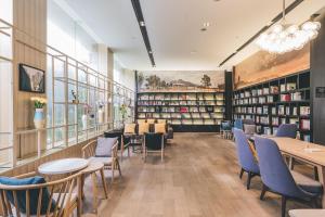 杭州杭州西湖亚朵音乐酒店的图书馆配有桌椅和书架