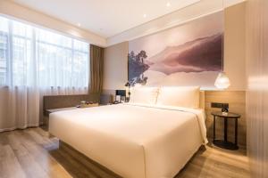花都广州花都广场地铁站亚朵酒店的卧室设有一张白色大床和大窗户