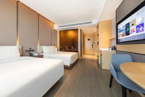 乌鲁木齐乌鲁木齐机场德港万达亚朵酒店的酒店客房设有两张床和一台平面电视。