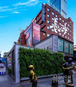 长沙长沙国金中心黄兴路步行街轻居酒店的两座雕像,站在一座建筑前面