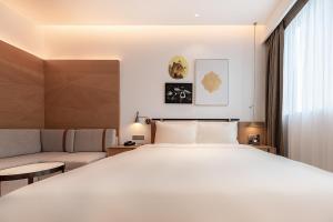 深圳深圳南山万科云城亚朵酒店的卧室配有一张白色的大床和一张沙发。