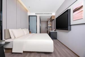 克拉玛依克拉玛依亚朵酒店的卧室配有白色的床和平面电视。