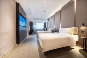 杭州杭州武林广场保俶路亚朵酒店的一间酒店客房,配有白色的床和一台平面电视