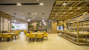 杭州杭州萧山人民广场亚朵酒店的一间设有黄色桌椅的餐厅和一间自助餐厅