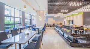 厦门厦门厦鼓邮轮中心亚朵酒店的一间设有桌子和蓝色椅子的餐厅以及自助餐