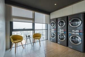 邯郸邯郸新世纪亚朵酒店的洗衣房配有4台洗衣机和2把椅子