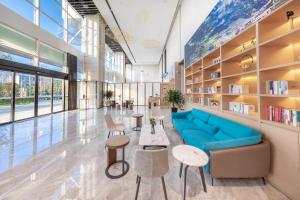昆明昆明市政府春融街亚朵酒店的图书馆配有蓝色的沙发和桌椅