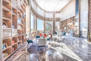 珠海金湾高栏港亚朵酒店的图书馆配有椅子和书架