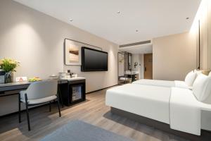 杭州杭州新天地中大银泰亚朵酒店的一间酒店客房,配有一张白色的床和一张书桌
