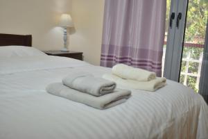 特里卡拉Rose's House的一张带白色毛巾的床,配有窗户
